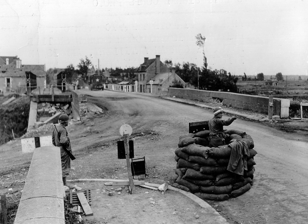 An MP directing traffic at a bridge under fire in Carentan